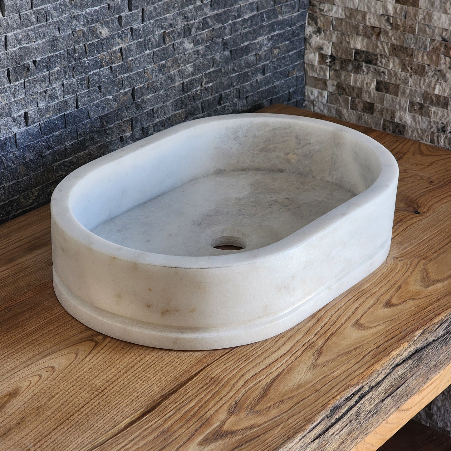 Norhew luxury oval white marble vessel sink with natural veining on a wooden vanity top