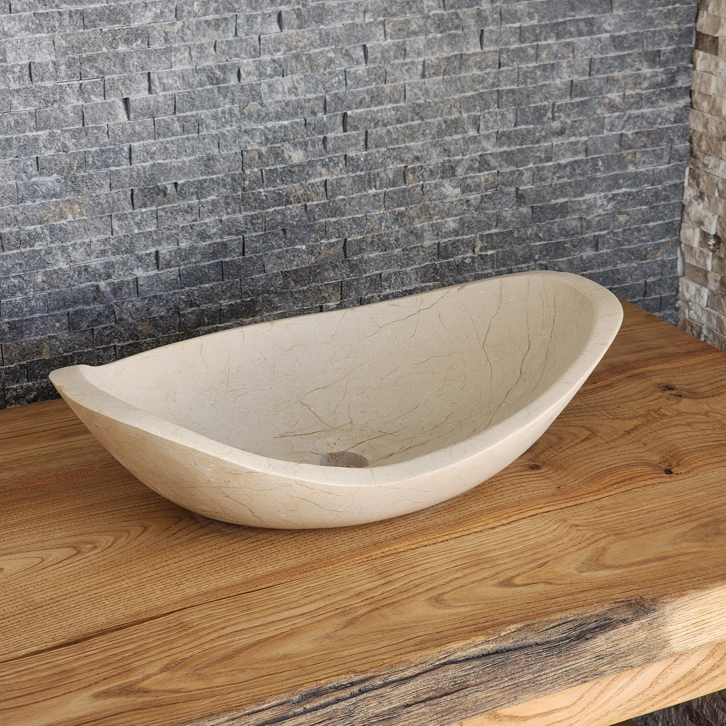 Norhew luxury cream stone boat-shaped vessel sink with an organic sweeping rim and subtle natural veining on a wooden vanity.