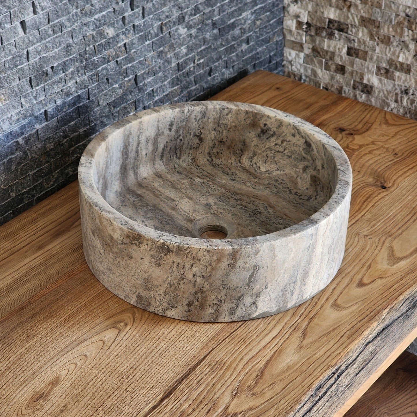 Norhew luxury round dark grey marble vessel sink featuring dramatic charcoal and white crystalline veining on a warm wood vanity.