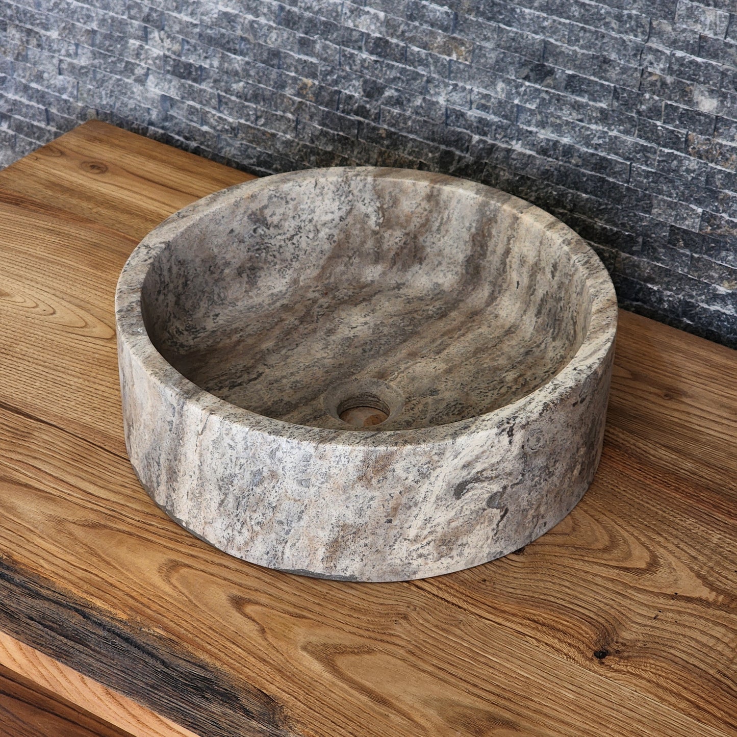 Norhew luxury round dark grey marble vessel sink featuring dramatic charcoal and white crystalline veining on a warm wood vanity.