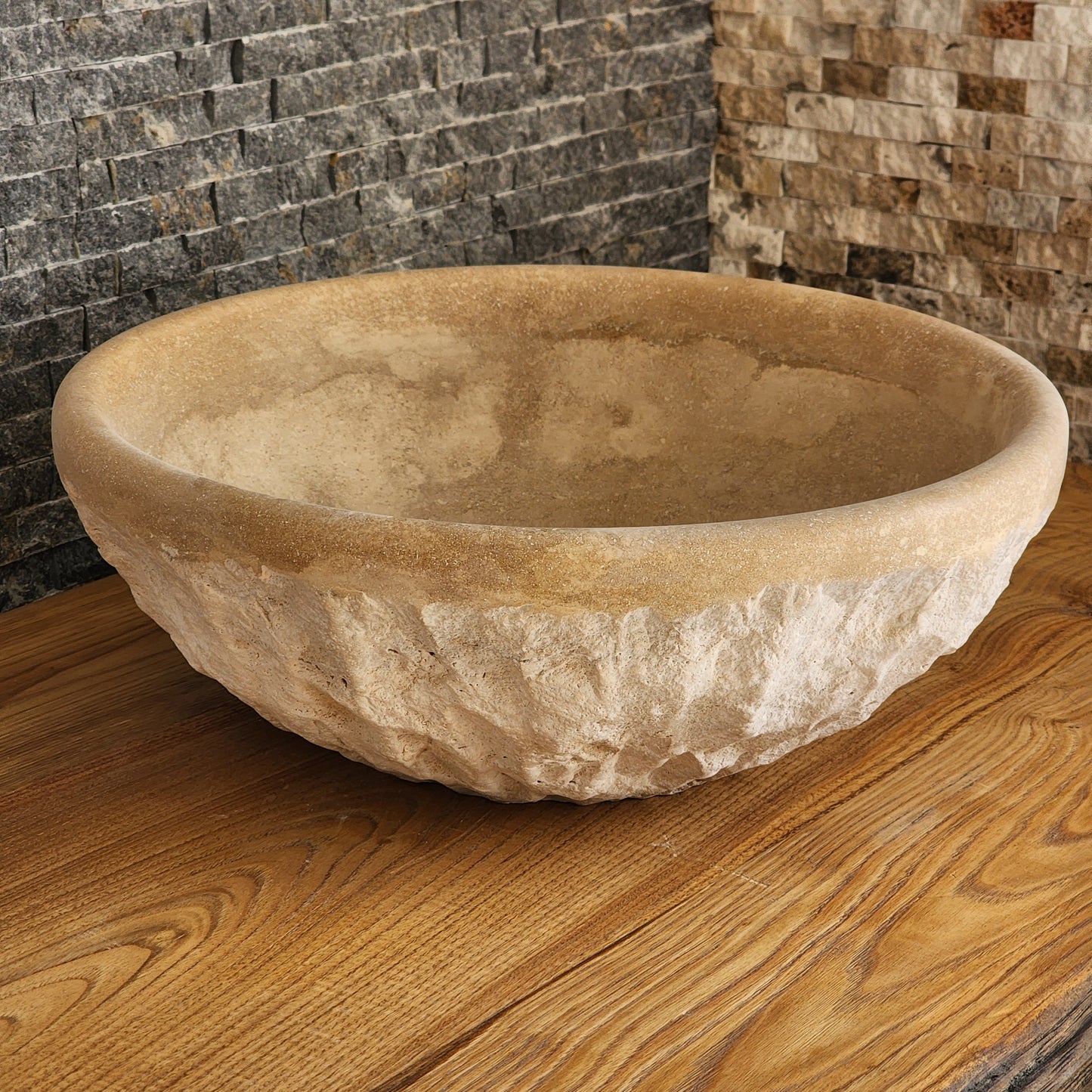 Norhew luxury round travertine vessel sink featuring a hand-chiseled raw exterior and a smooth honed interior on a rustic wood vanity.