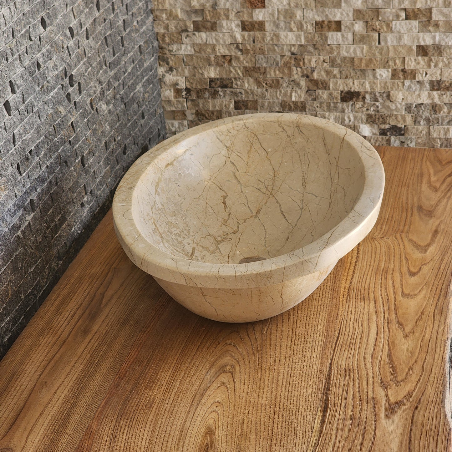 Norhew luxury oval beige breccia marble vessel sink with a classic flared rim and intricate natural veining on a wooden vanity.