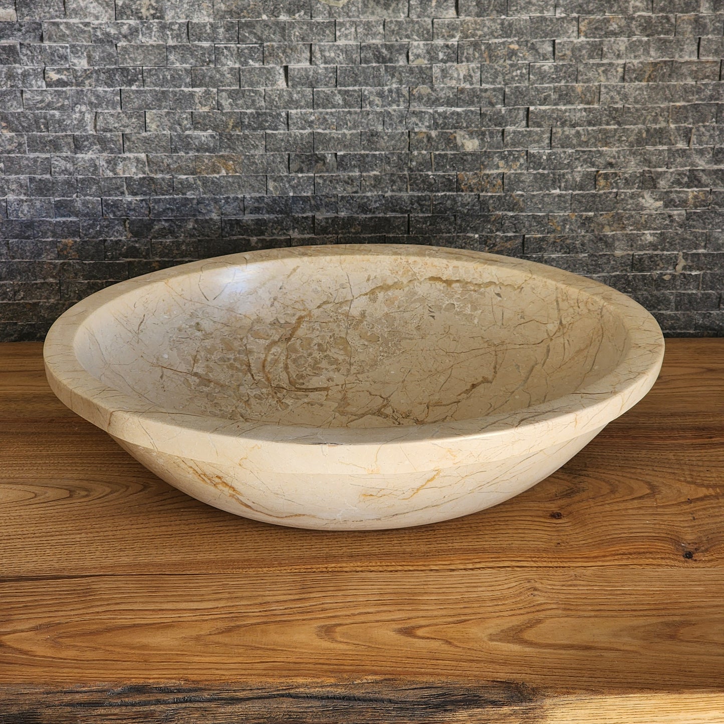 Norhew luxury oval beige breccia marble vessel sink with a classic flared rim and intricate natural veining on a wooden vanity.