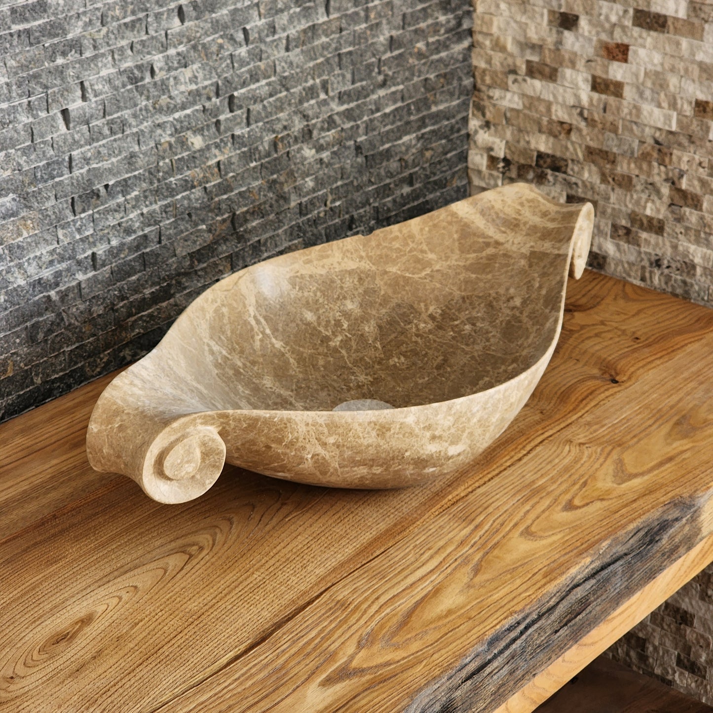 Norhew luxury beige marble boat-shaped vessel sink with hand-carved scroll spiral edges on a natural oak vanity.
