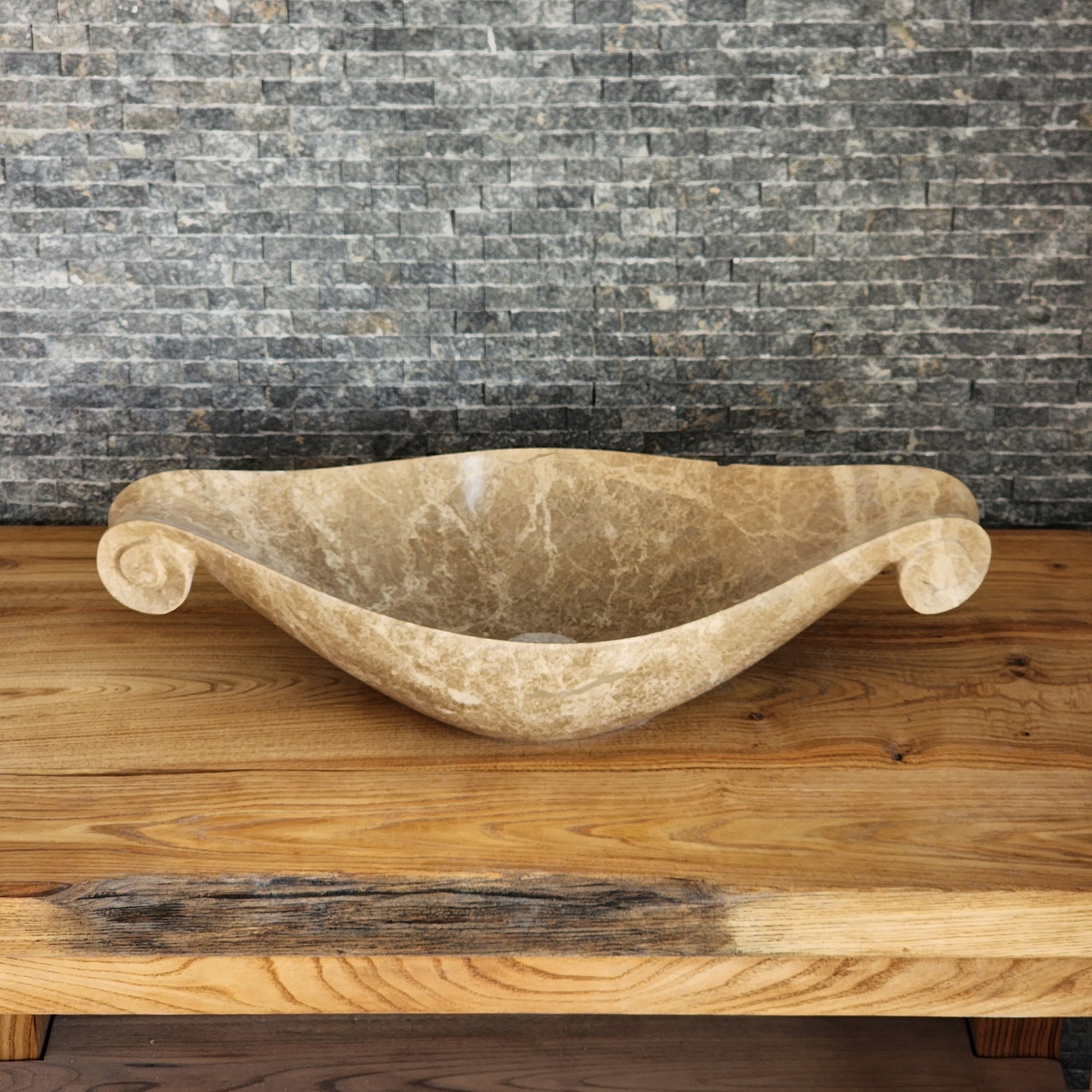 Norhew luxury beige marble boat-shaped vessel sink with hand-carved scroll spiral edges on a natural oak vanity.