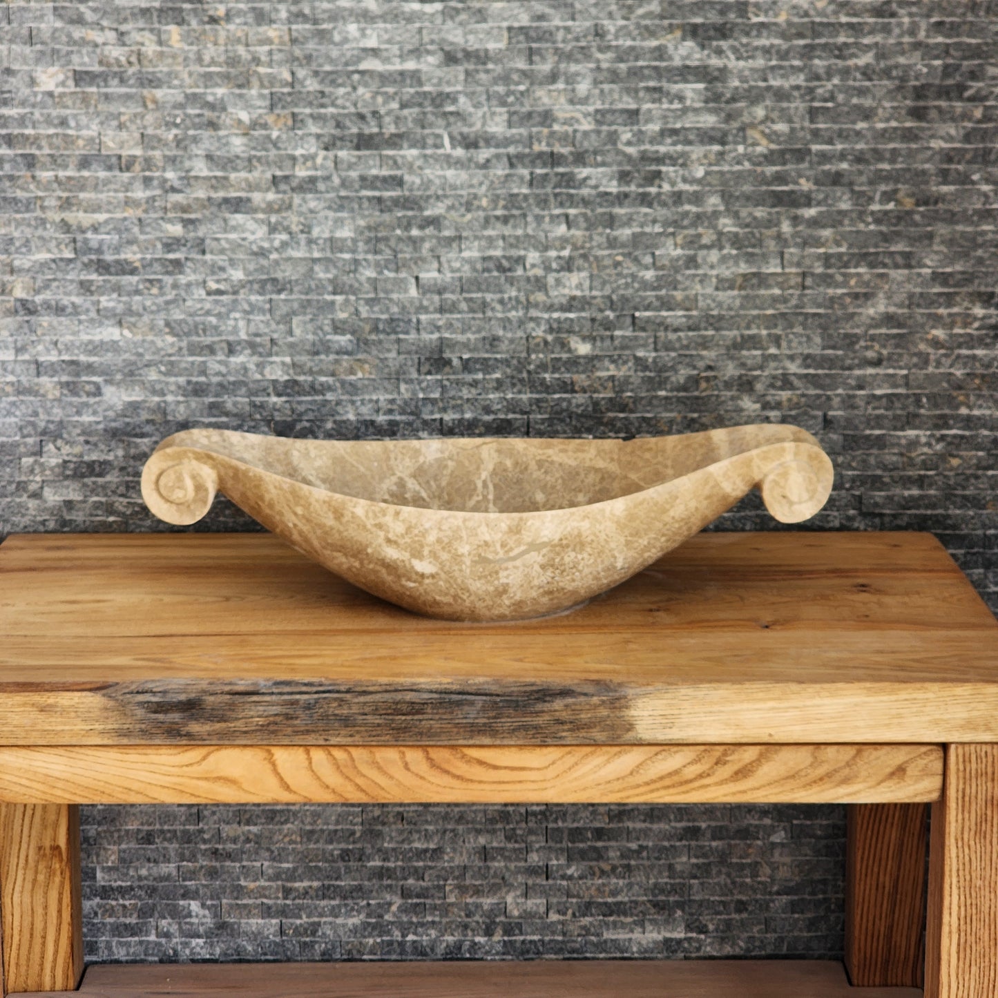 Norhew luxury beige marble boat-shaped vessel sink with hand-carved scroll spiral edges on a natural oak vanity.