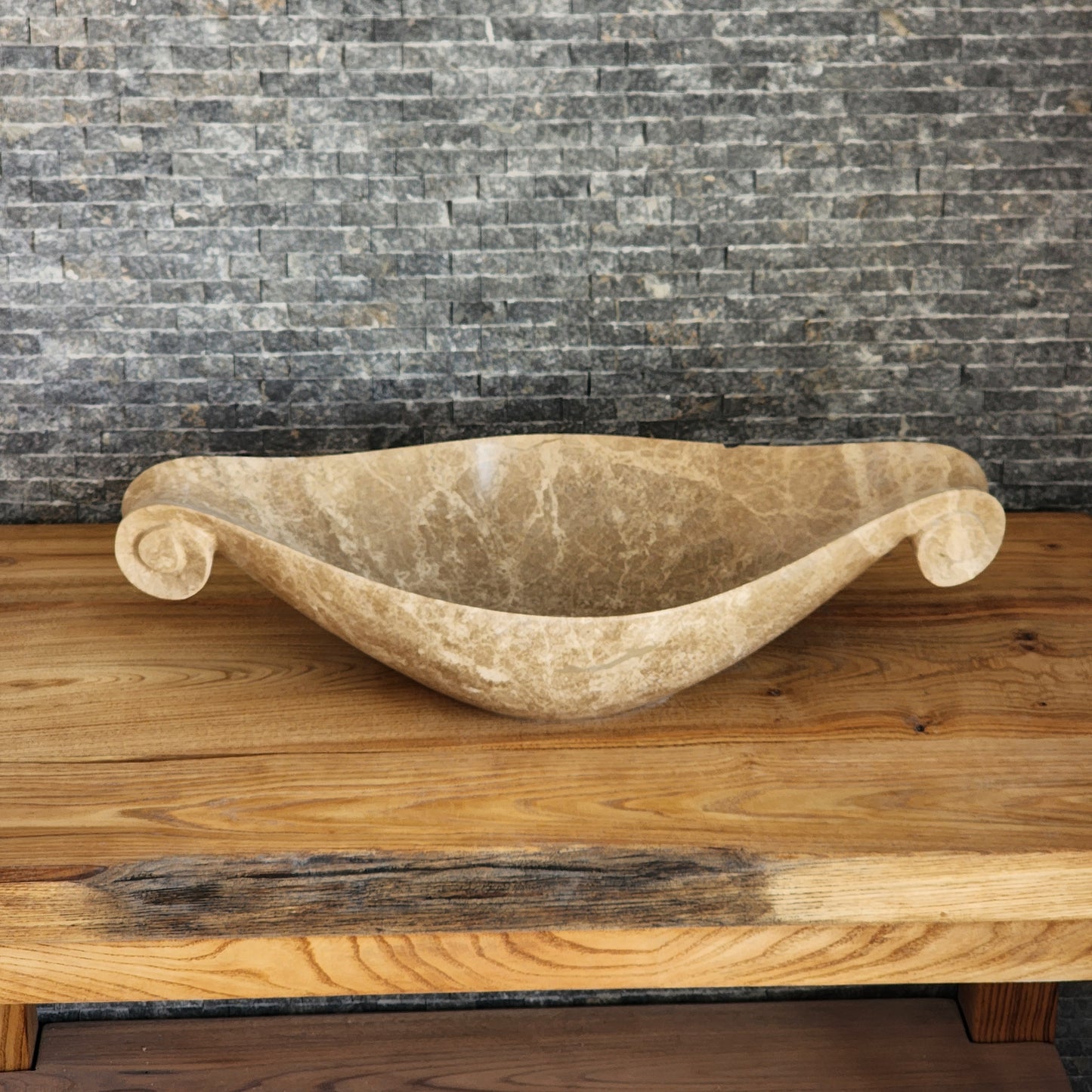 Norhew luxury beige marble boat-shaped vessel sink with hand-carved scroll spiral edges on a natural oak vanity.