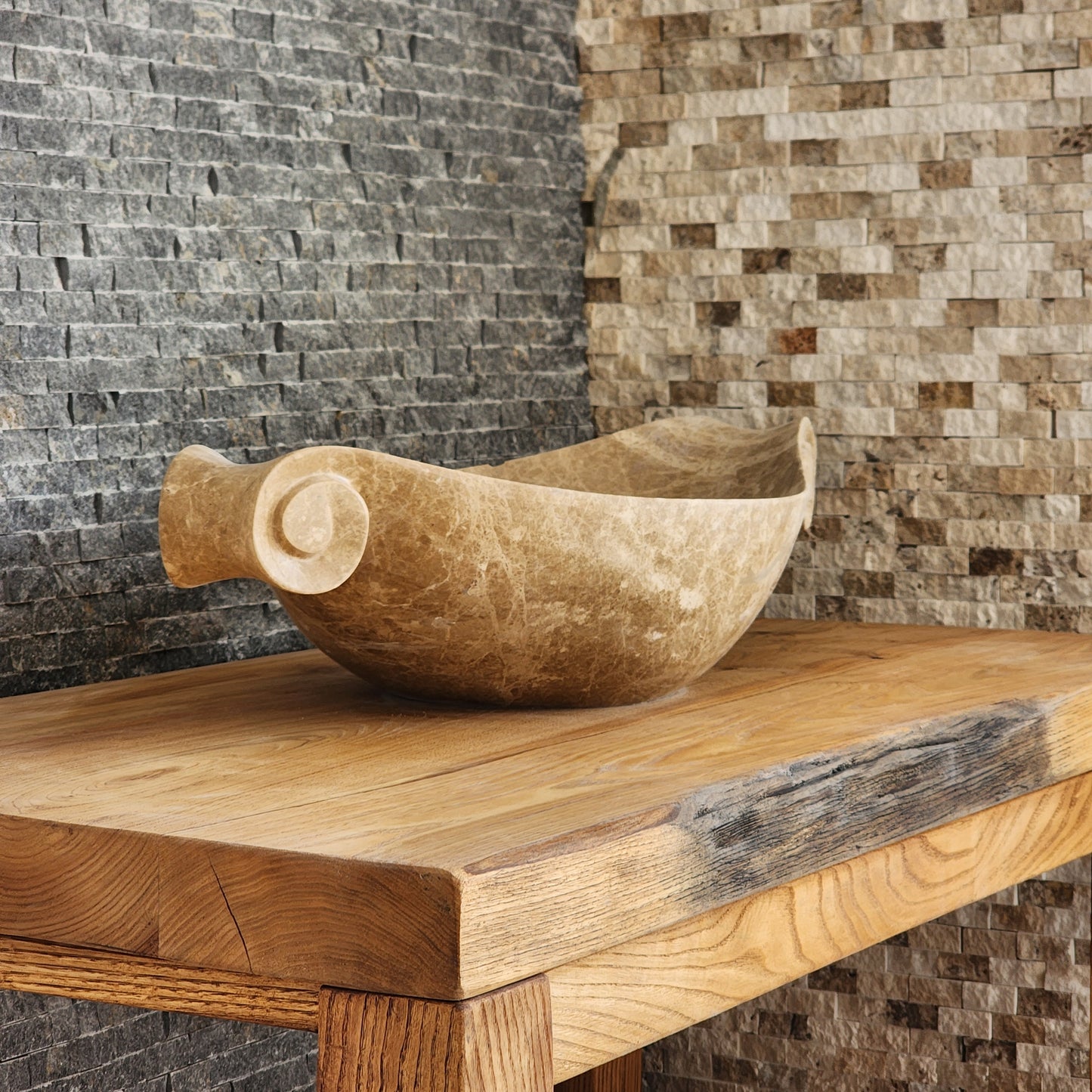 Norhew luxury beige marble boat-shaped vessel sink with hand-carved scroll spiral edges on a natural oak vanity.