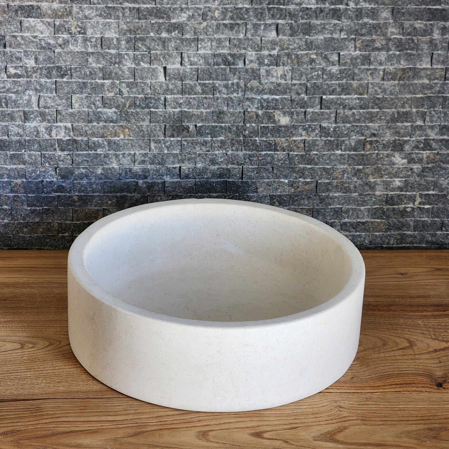 Norhew luxury round cream marble vessel sink featuring a distinctive flared rim and polished finish on a warm wood vanity.