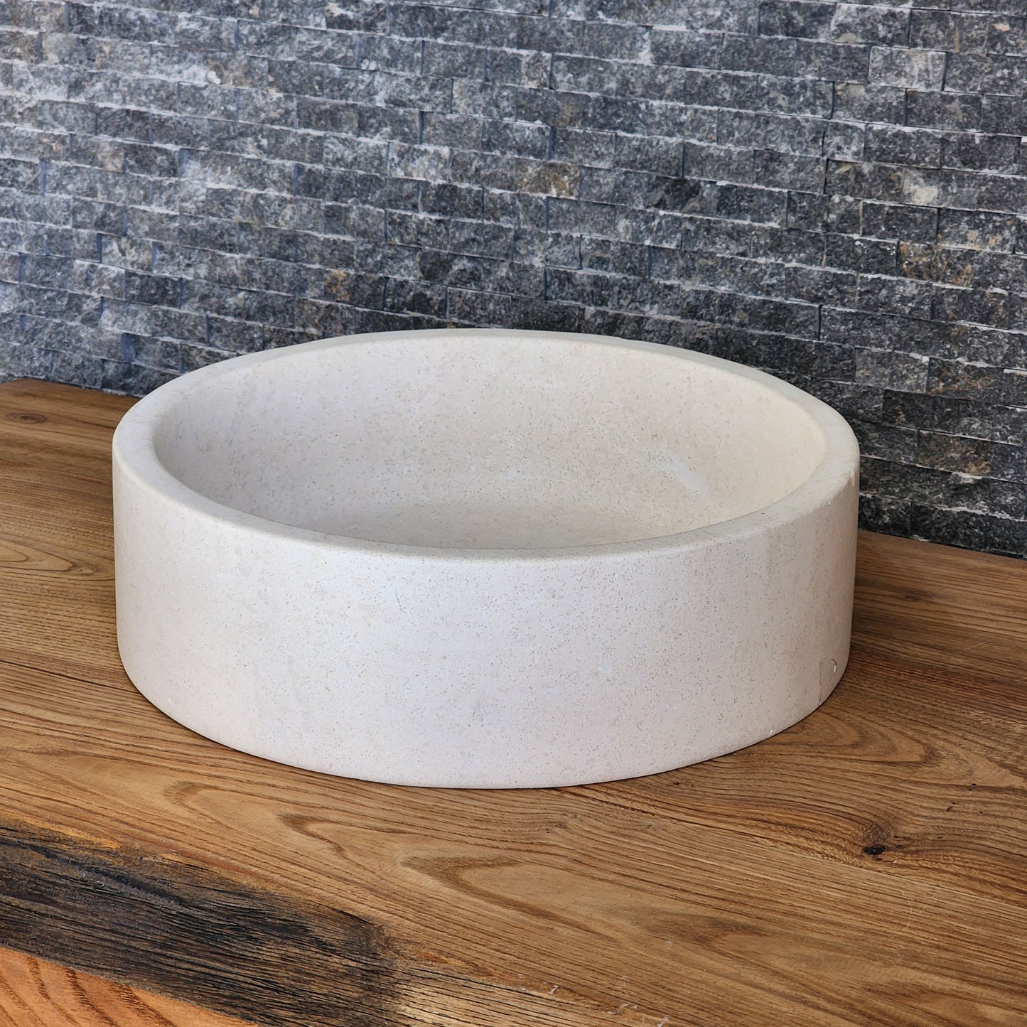 Norhew luxury round cream marble vessel sink featuring a distinctive flared rim and polished finish on a warm wood vanity.