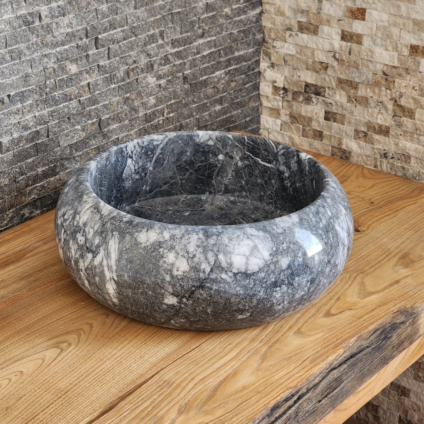 Norhew luxury round gray storm marble vessel sink with dramatic charcoal and white crystalline veining on a rustic oak vanity.