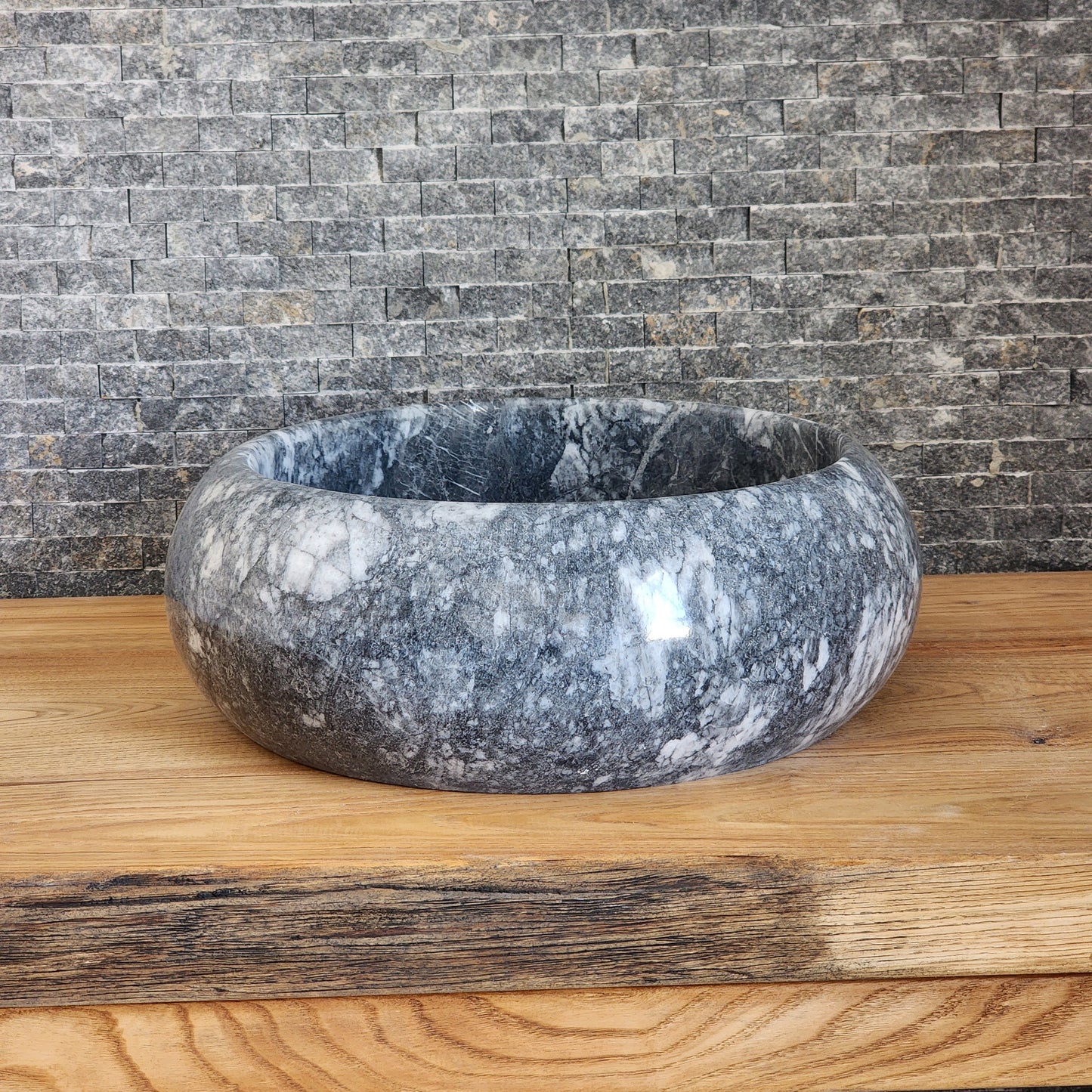 Norhew luxury round gray storm marble vessel sink with dramatic charcoal and white crystalline veining on a rustic oak vanity.