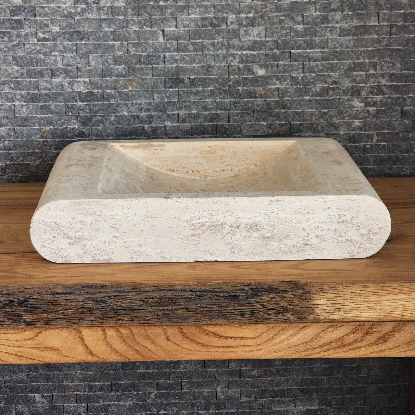 Norhew luxury rectangular travertine vessel sink with a sloped infinity interior and smooth radius-curved edges on a wooden vanity.