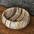 Switch Norhew luxury striped onyx vessel sink featuring natural honey and amber translucent banding on a modern wooden vanity. 2 image