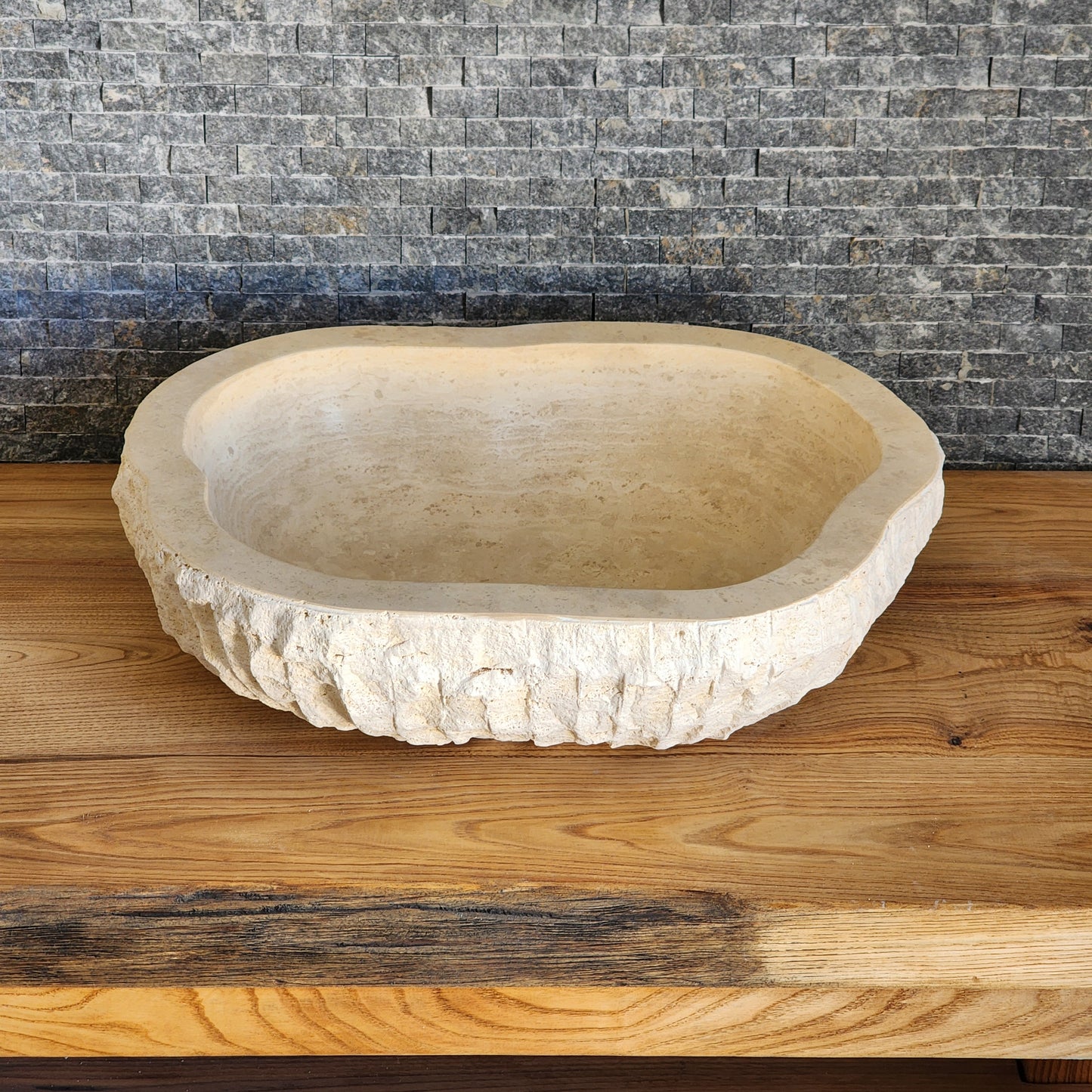 Norhew luxury organic oval travertine vessel sink with a hand-chiseled raw exterior and a smooth honed interior on a solid wood vanity