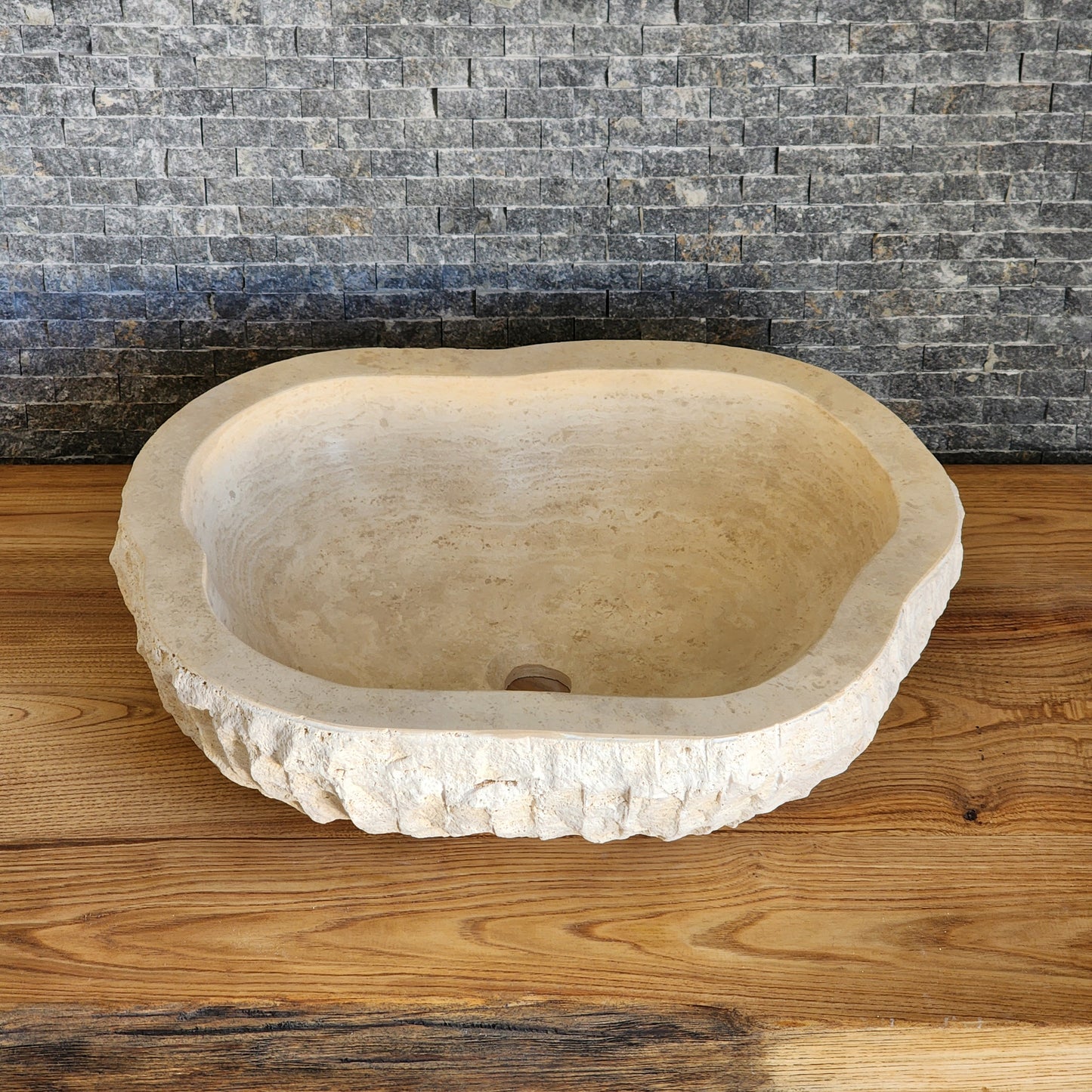 Norhew luxury organic oval travertine vessel sink with a hand-chiseled raw exterior and a smooth honed interior on a solid wood vanity