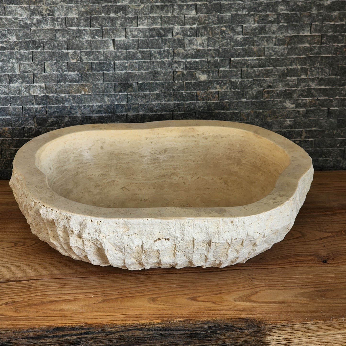 Norhew luxury organic oval travertine vessel sink with a hand-chiseled raw exterior and a smooth honed interior on a solid wood vanity