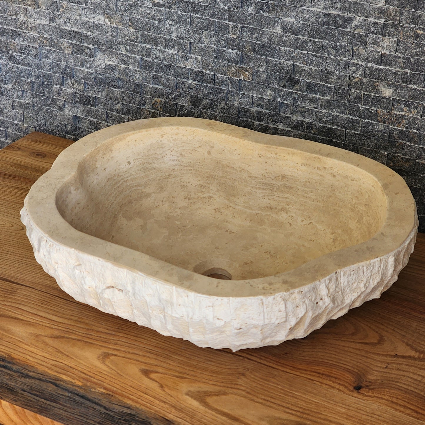 Norhew luxury organic oval travertine vessel sink with a hand-chiseled raw exterior and a smooth honed interior on a solid wood vanity