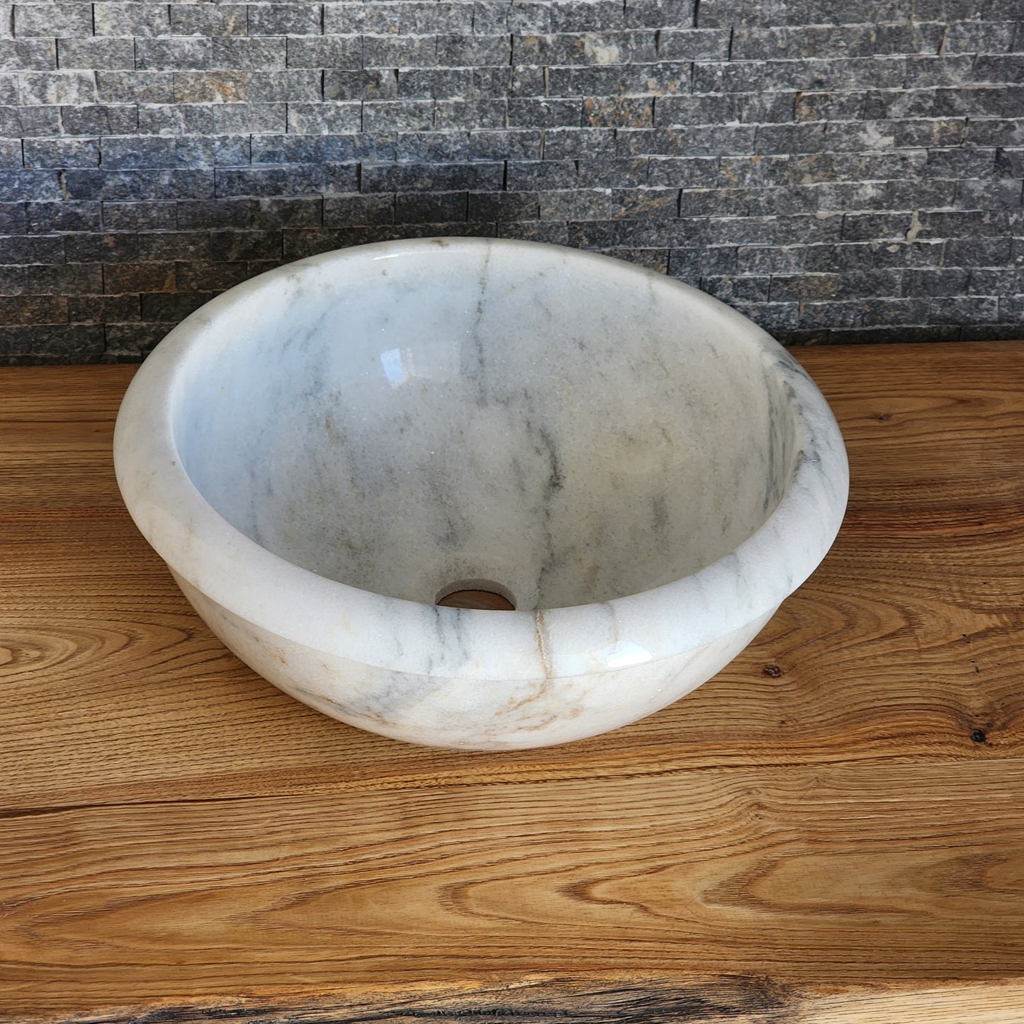 Norhew luxury white marble oval vessel sink with natural grey veining and a tiered base on a rustic wood vanity