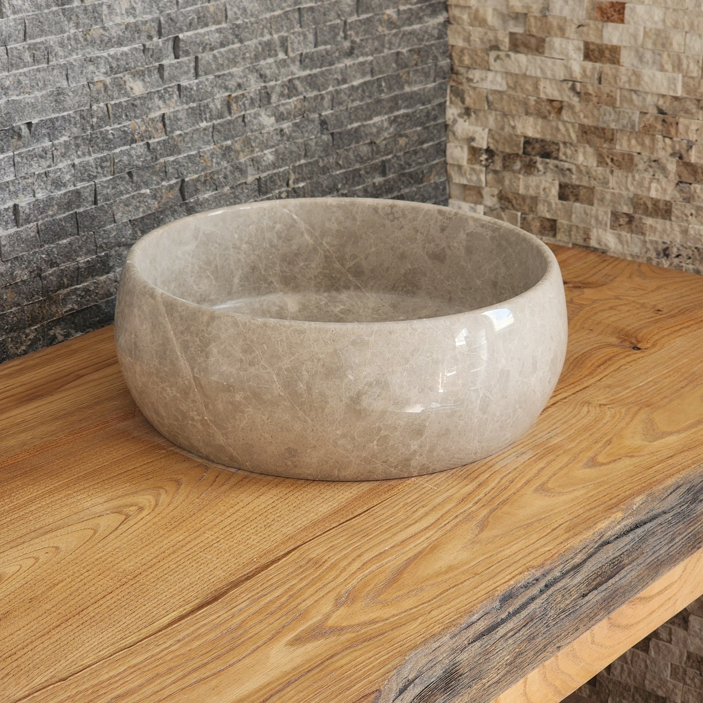 Norhew luxury round taupe marble vessel sink with a high-polish finish and delicate white branching veining on a light oak vanity.