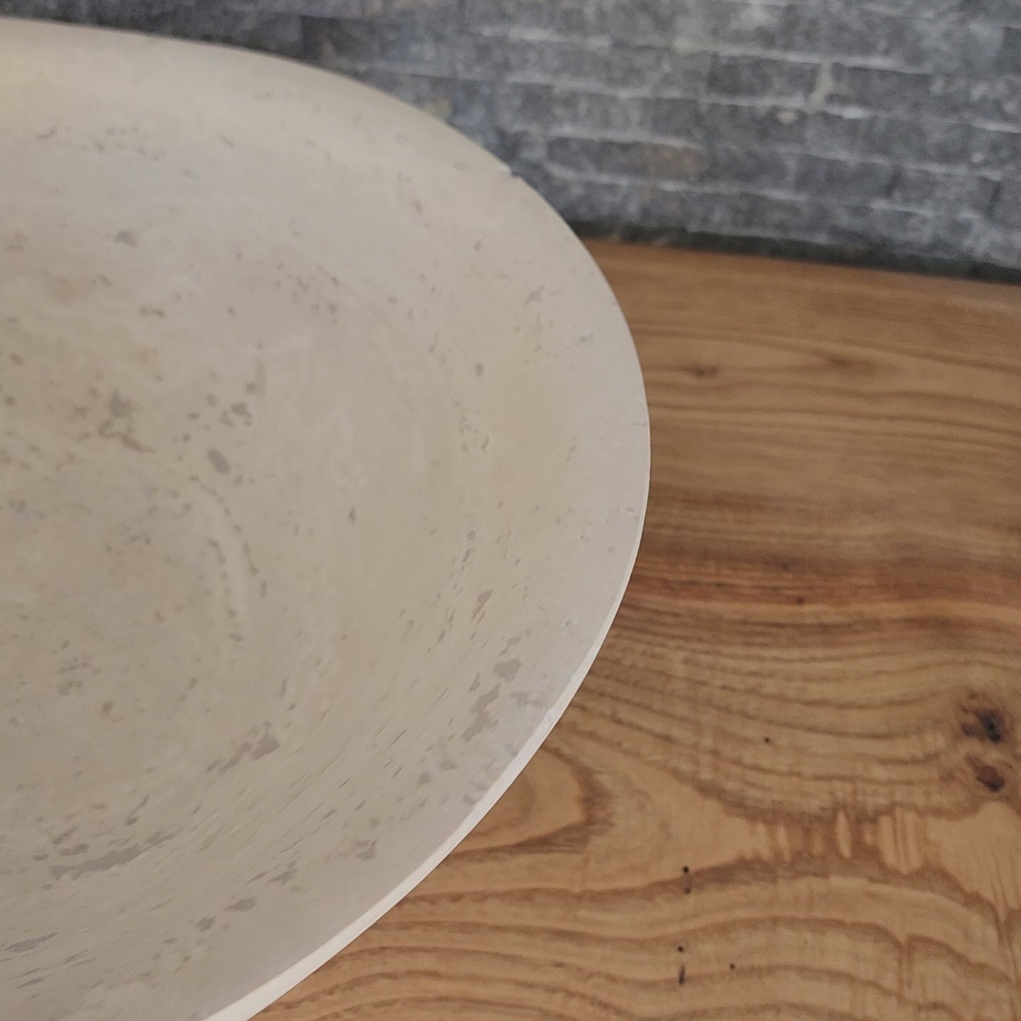 Norhew luxury travertine oval vessel sink with natural cream pitting and a honed finish on a solid wood vanity.