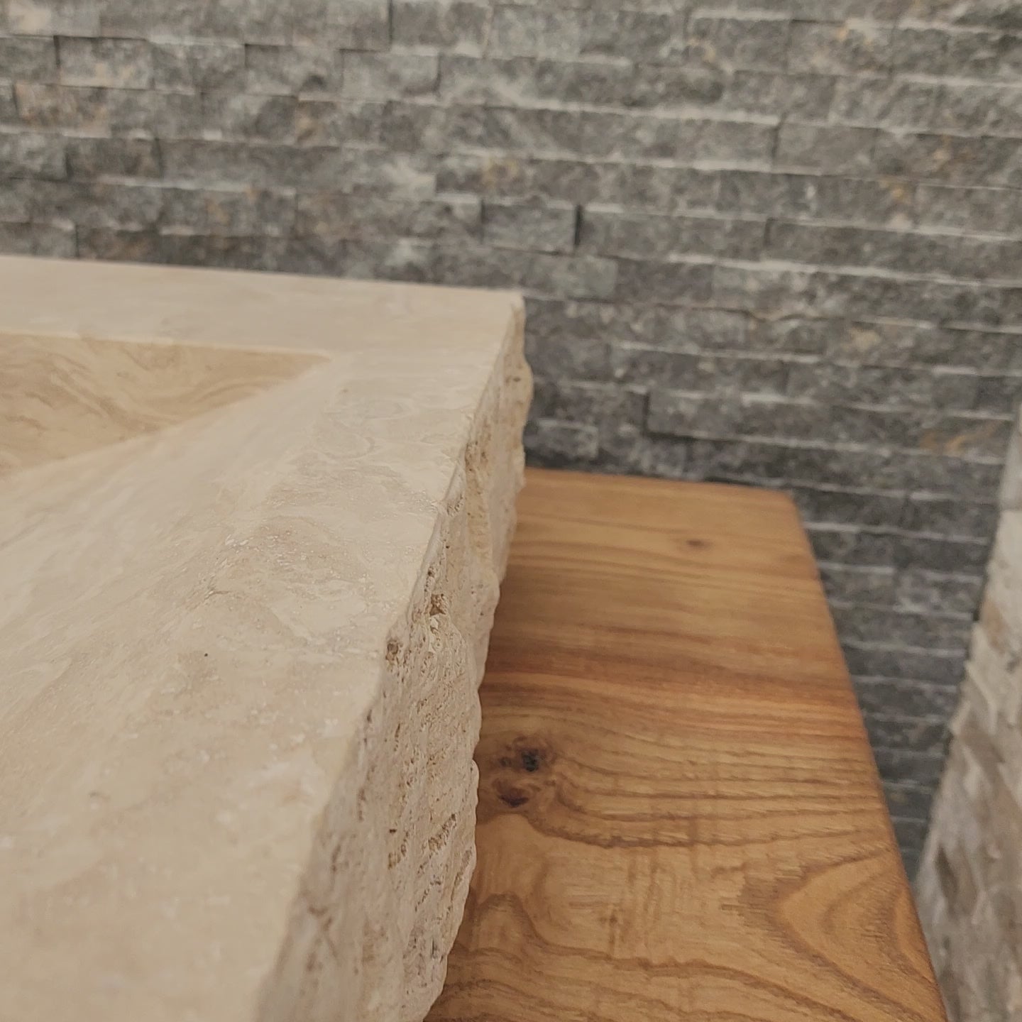 Norhew luxury large rectangular travertine trough sink with a hand-chiseled raw exterior and a wide smooth interior on a wooden vanity.