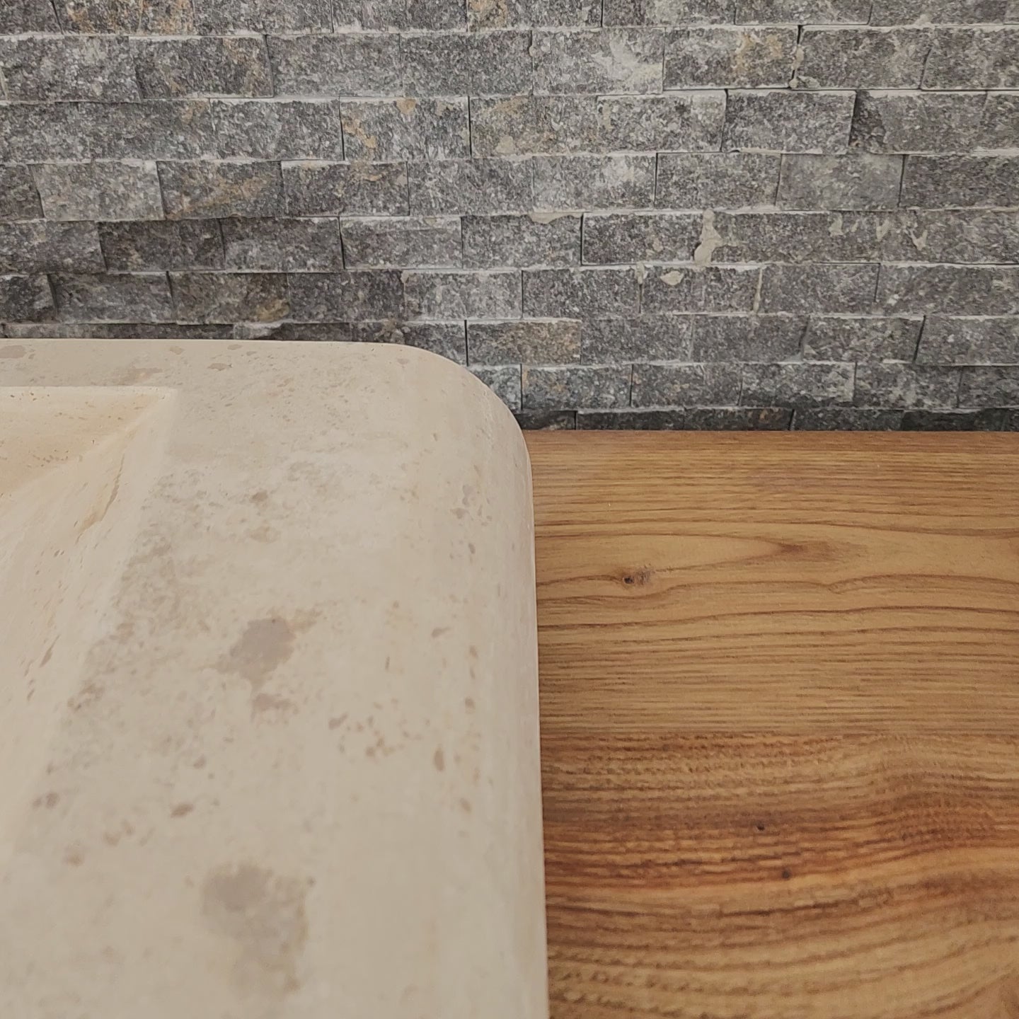 Norhew luxury rectangular travertine vessel sink with a sloped infinity interior and smooth radius-curved edges on a wooden vanity.