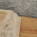 Switch Norhew luxury rectangular travertine vessel sink featuring a chiseled raw stone exterior and a smooth honed interior on a wooden vanity. 2 image
