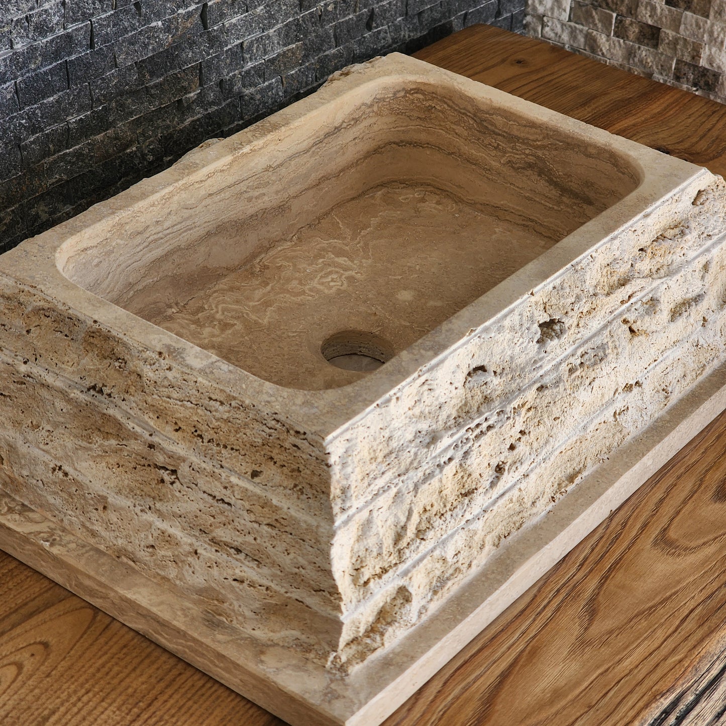 Norhew luxury rectangular travertine vessel sink featuring a chiseled raw stone exterior and a smooth honed interior on a wooden vanity.