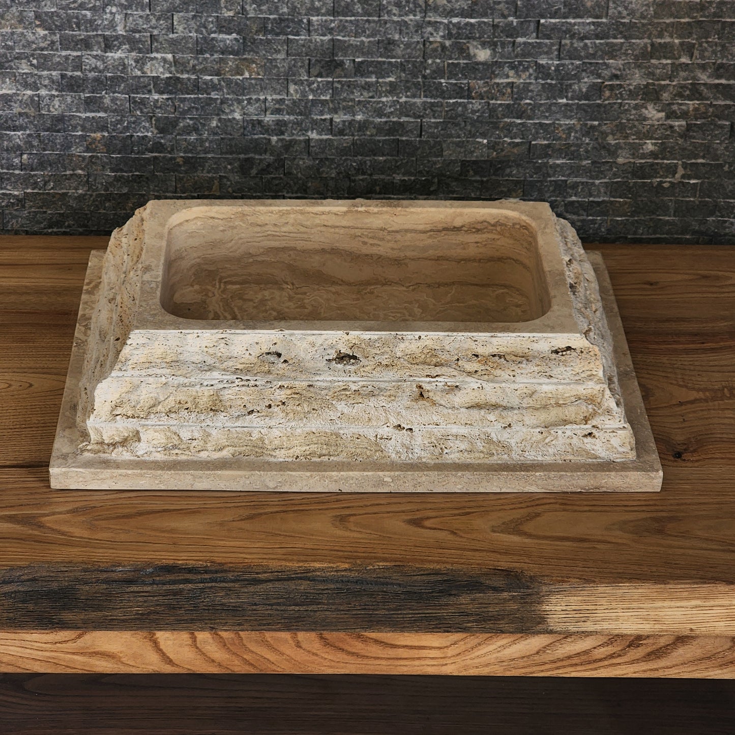 Norhew luxury rectangular travertine vessel sink featuring a chiseled raw stone exterior and a smooth honed interior on a wooden vanity.