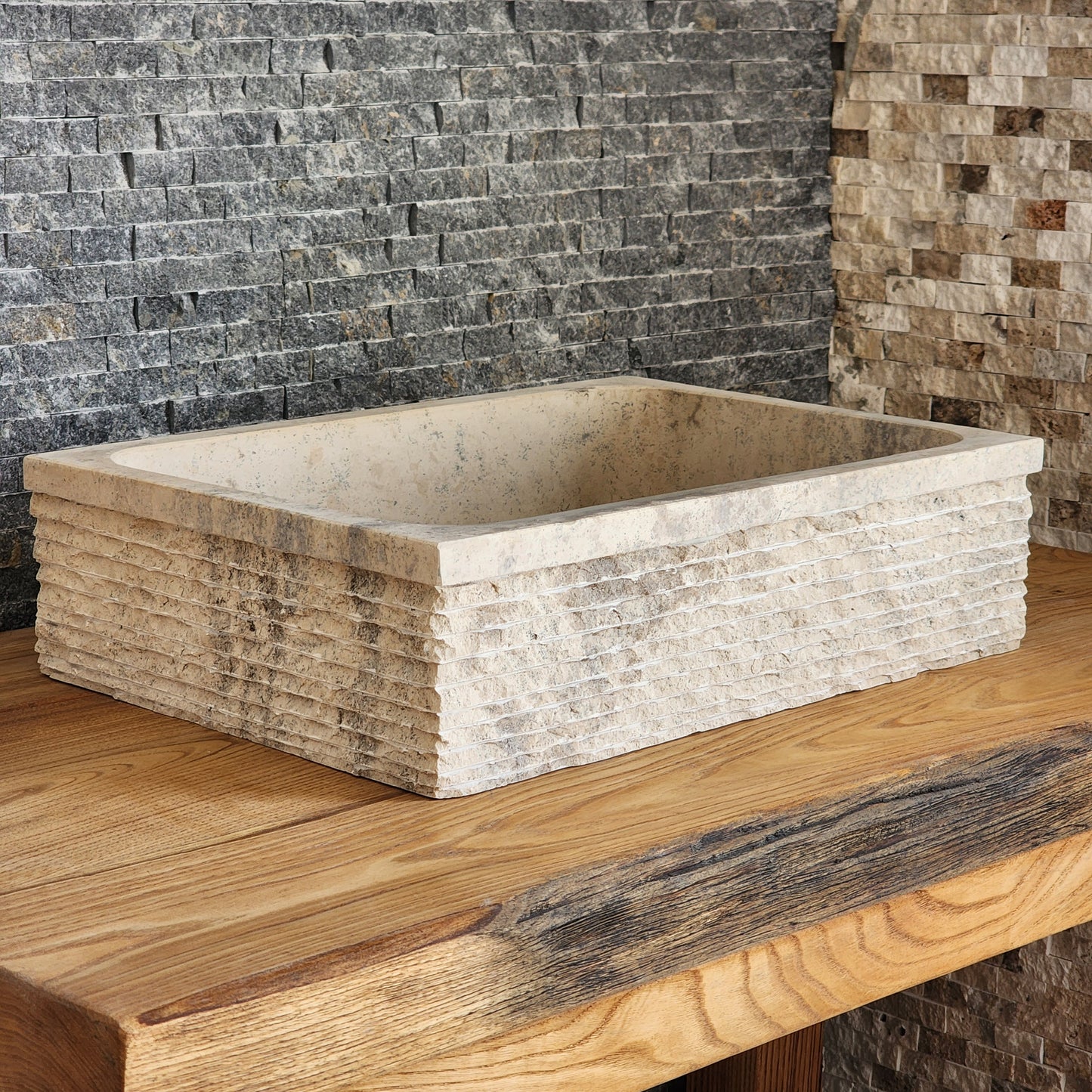 Norhew luxury rectangular travertine vessel sink featuring a hand-chiseled raw stone exterior and a smooth honed interior on a solid wood vanity.