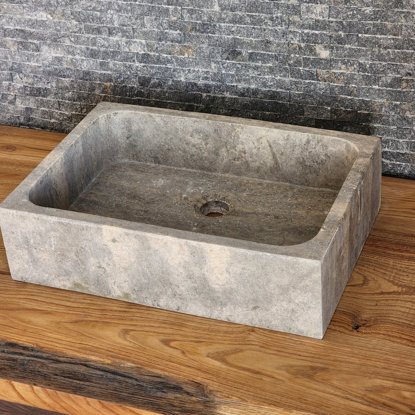 Norhew luxury rectangular silver travertine vessel sink with a honed grey-beige finish and solid block silhouette on a wooden vanity.