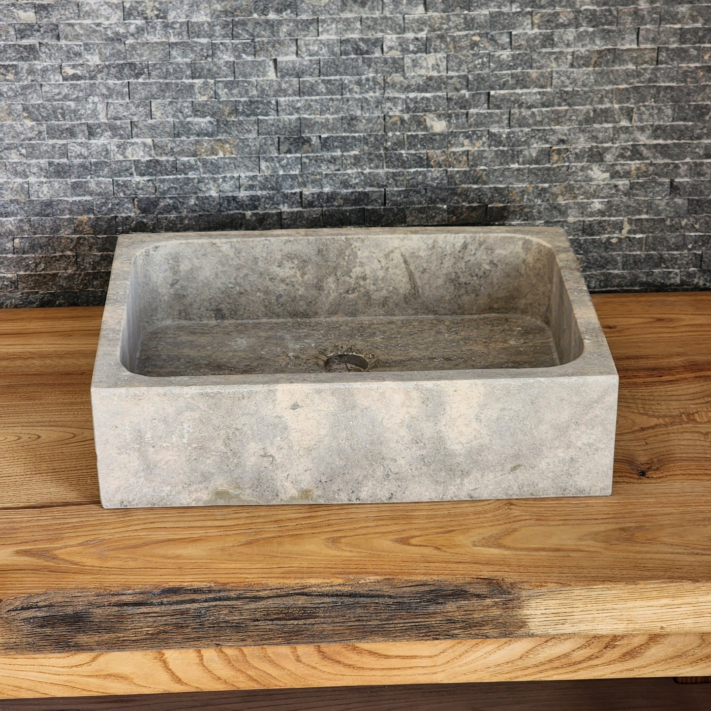 Norhew luxury rectangular silver travertine vessel sink with a honed grey-beige finish and solid block silhouette on a wooden vanity.