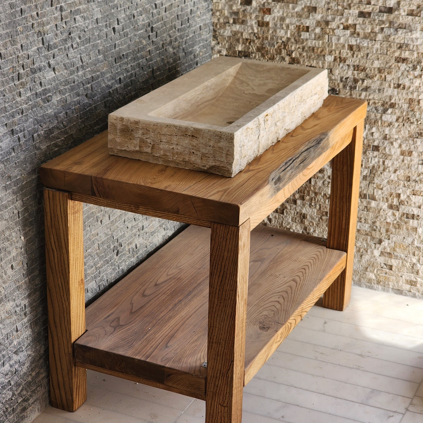 Norhew luxury large rectangular travertine trough sink with a hand-chiseled raw exterior and a wide smooth interior on a wooden vanity.