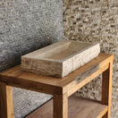 Switch Norhew luxury large rectangular travertine trough sink with a hand-chiseled raw exterior and a wide smooth interior on a wooden vanity. 3 image