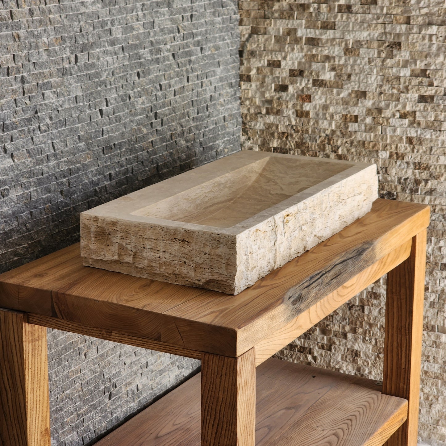 Norhew luxury large rectangular travertine trough sink with a hand-chiseled raw exterior and a wide smooth interior on a wooden vanity.