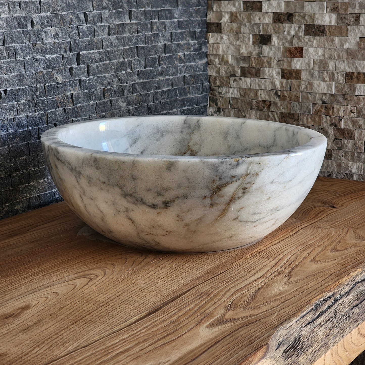 luxury round white marble vessel sink with a thick architectural rim and natural grey veining on a warm wood vanity.