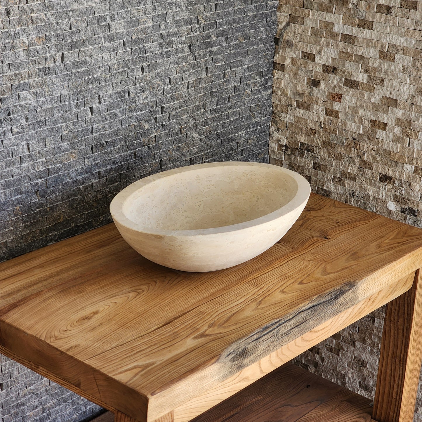 Norhew luxury round solid travertine vessel sink with natural golden-beige pitting and a thick-rimmed profile on a wooden vanity.