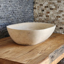 Switch Norhew luxury travertine oval vessel sink with natural cream pitting and a honed finish on a solid wood vanity. 2 image