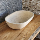 Switch Norhew luxury travertine oval vessel sink with natural cream pitting and a honed finish on a solid wood vanity. 3 image